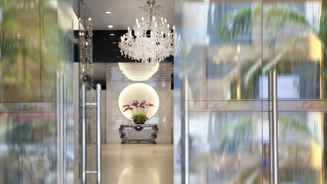 Lobby with mirror and flower vase at Silka Maytower Hotel