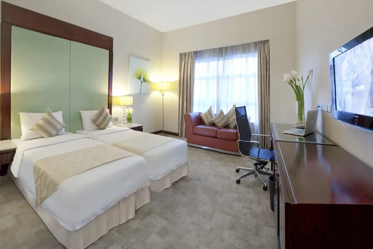 Twin beds, work desk, and city view at Silka Maytower Deluxe Room