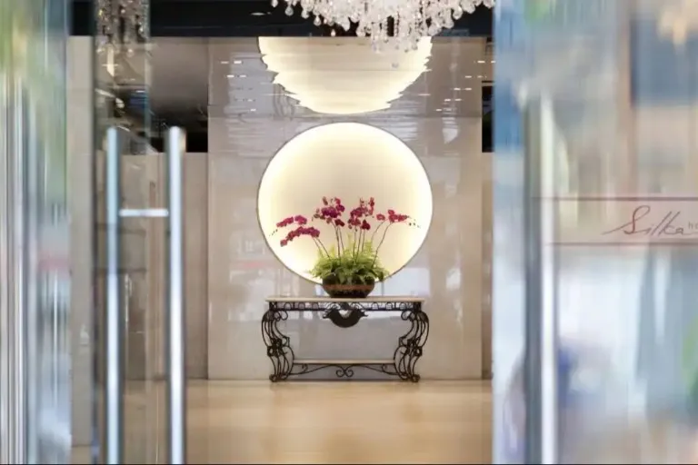 Lobby with mirror and flower vase at Silka Maytower Hotel