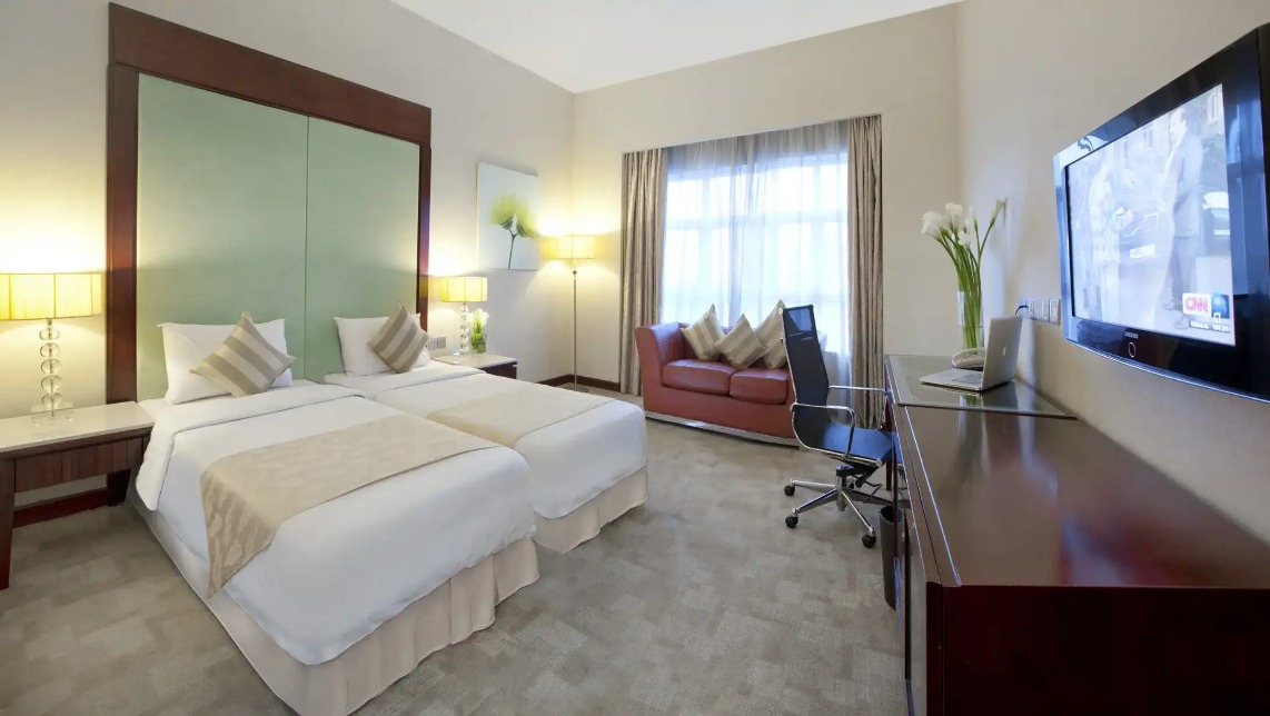 Twin beds, work desk, and city view at Silka Maytower Deluxe Room